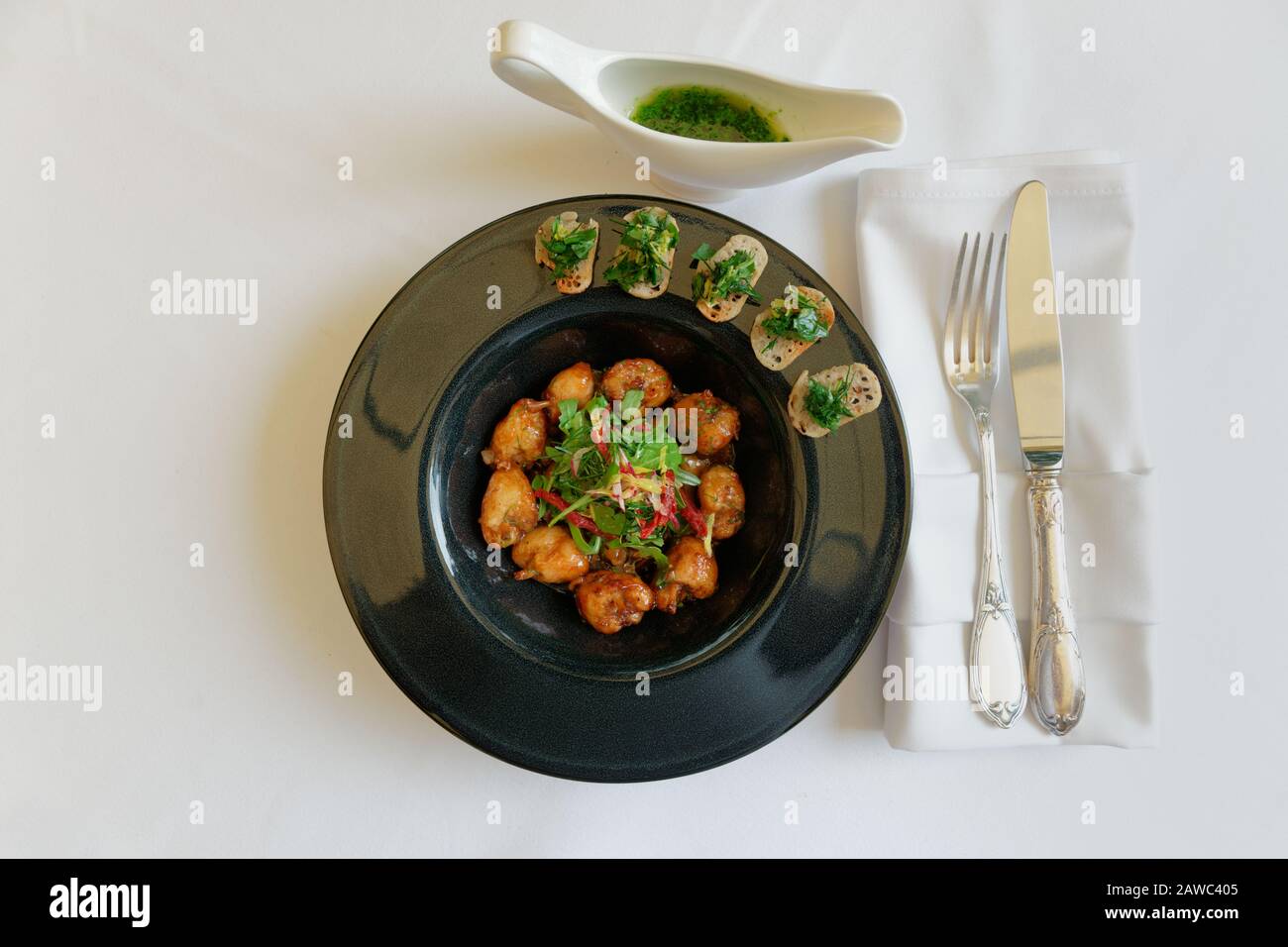 Pattes de grenouille frite dans une plaque noire sur la table du restaurant tourné d'en haut, plat français Banque D'Images