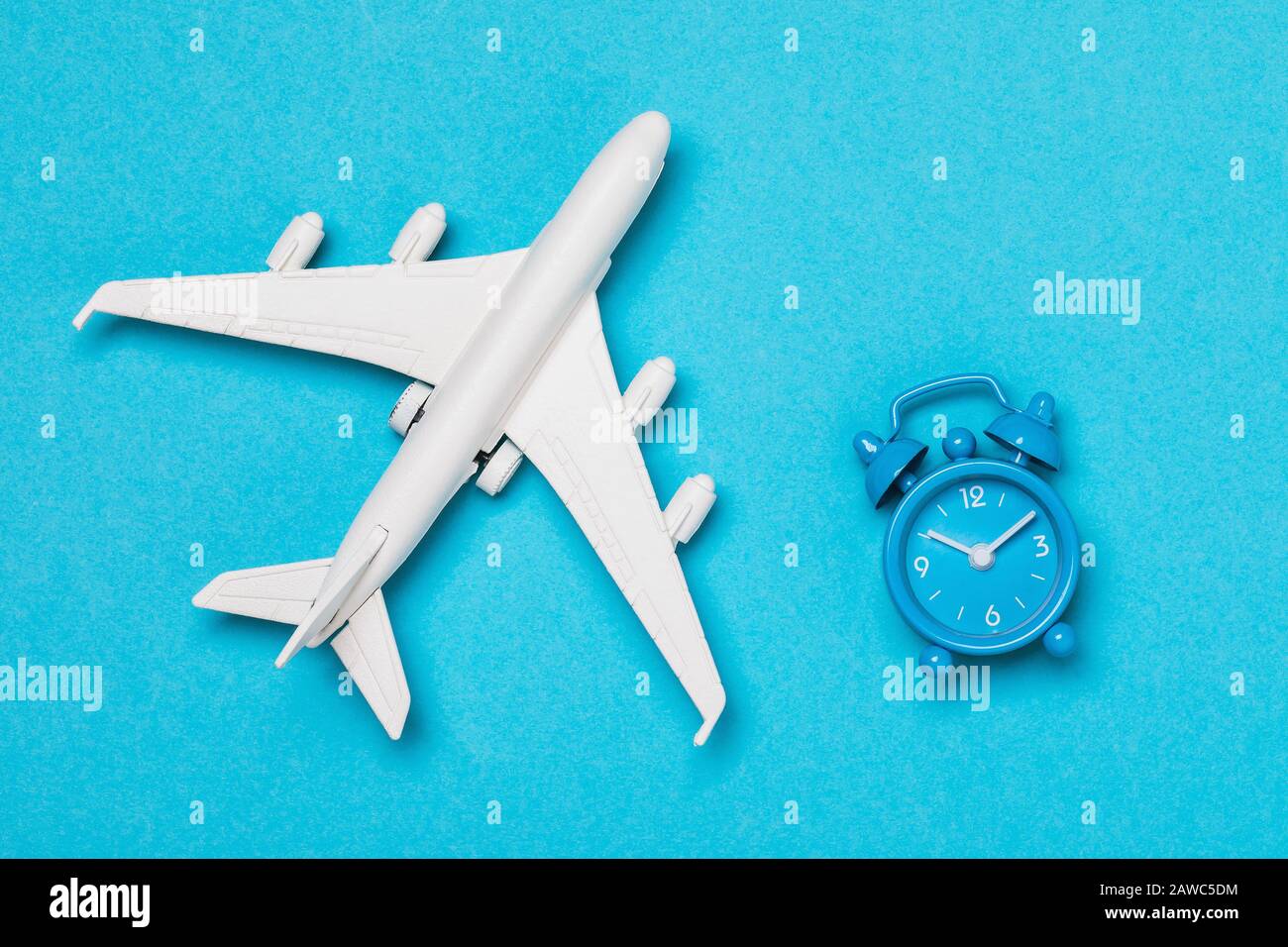 Avion et horloge sur fond bleu, vue de dessus. Le concept de la durée des vols Banque D'Images