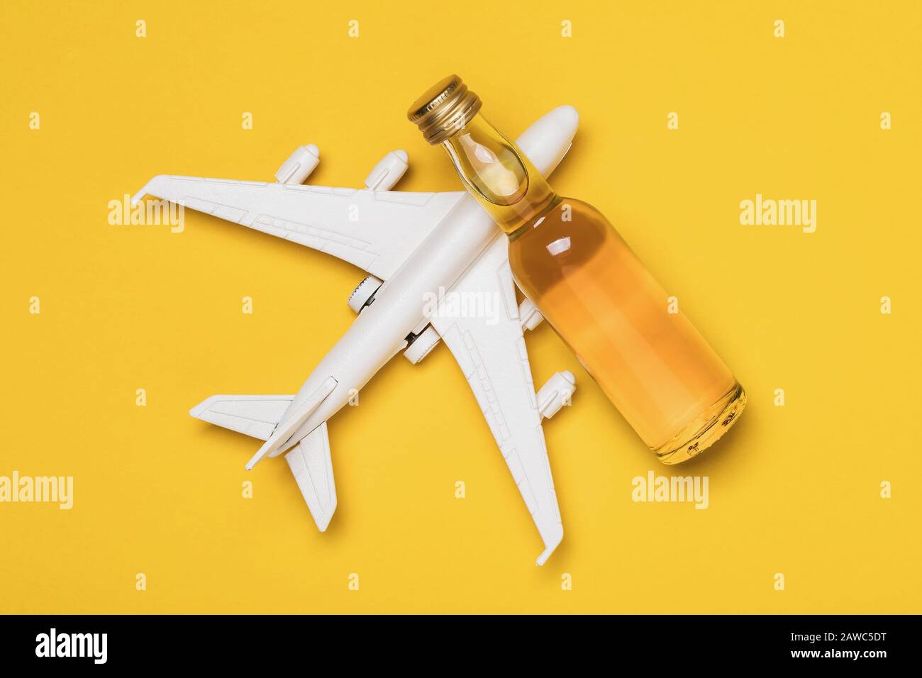 Avion et bouteille de whisky sur fond jaune, vue de dessus. Concept sur le sujet de l'ivresse parmi les pilotes. Banque D'Images