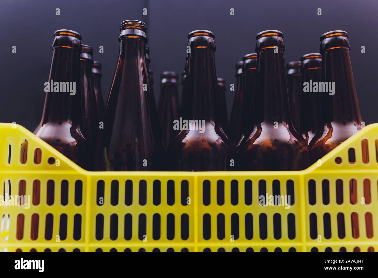 Caisse de bière jaune vintage poussiéreuse avec bouteilles de bière brune vides sur fond blanc Banque D'Images