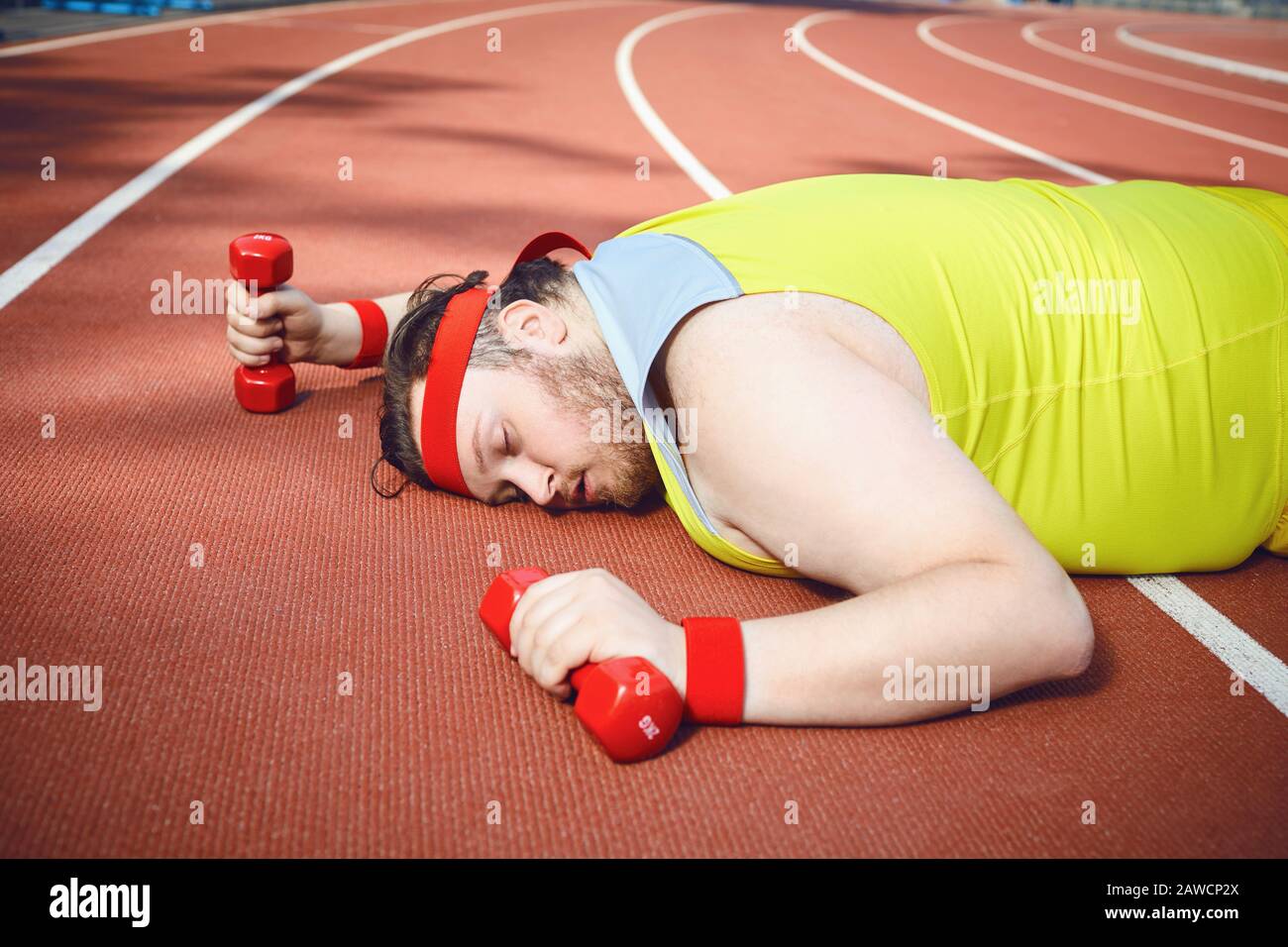 FAT paresseux dort fatigué se trouve sur la piste dans le stade. Banque D'Images