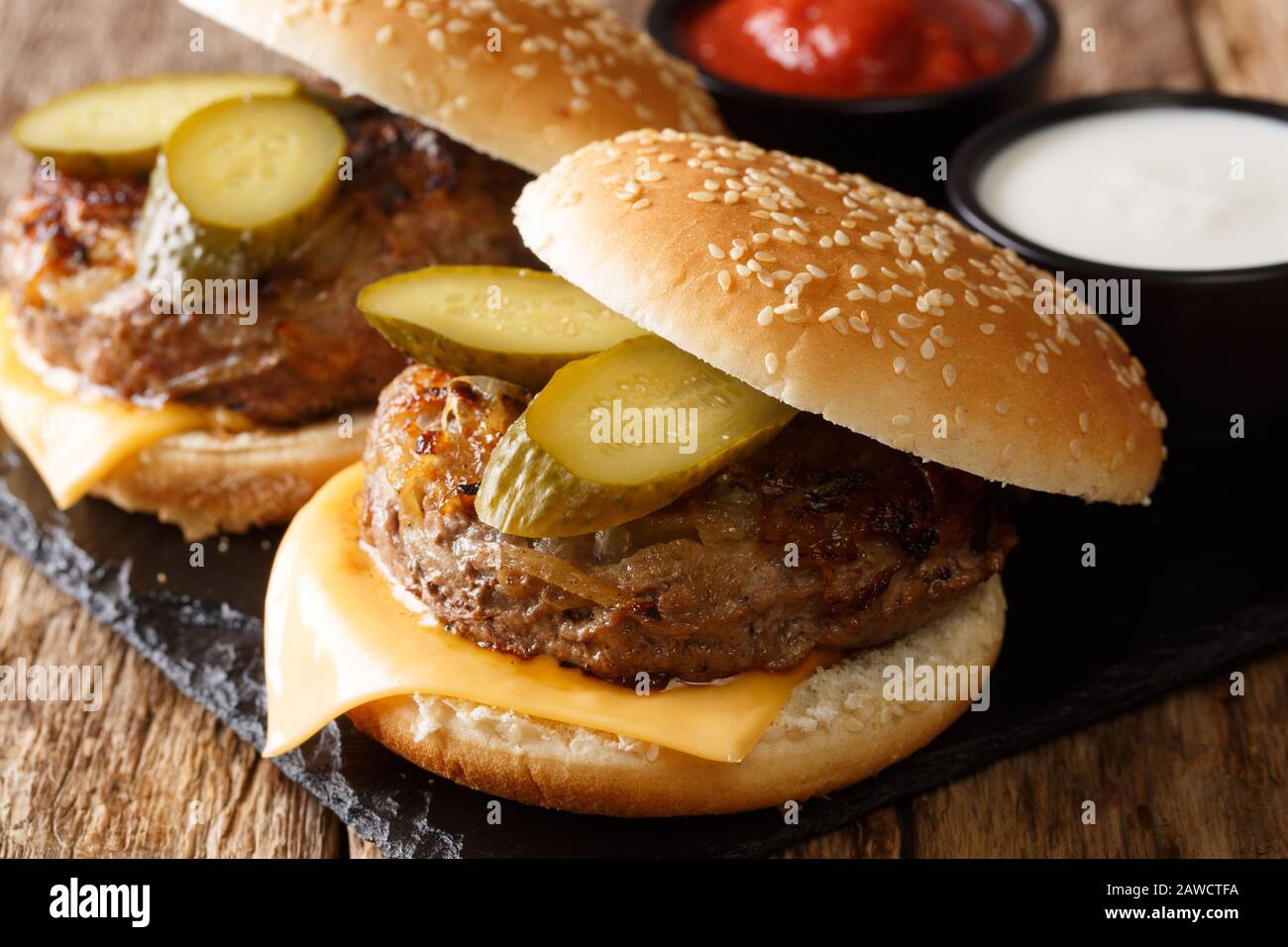 Hamburger traditionnel à l'oignon de l'Oklahoma servi avec ketchup et mayonnaise sur une planche en ardoise sur une table. Horizontal Banque D'Images