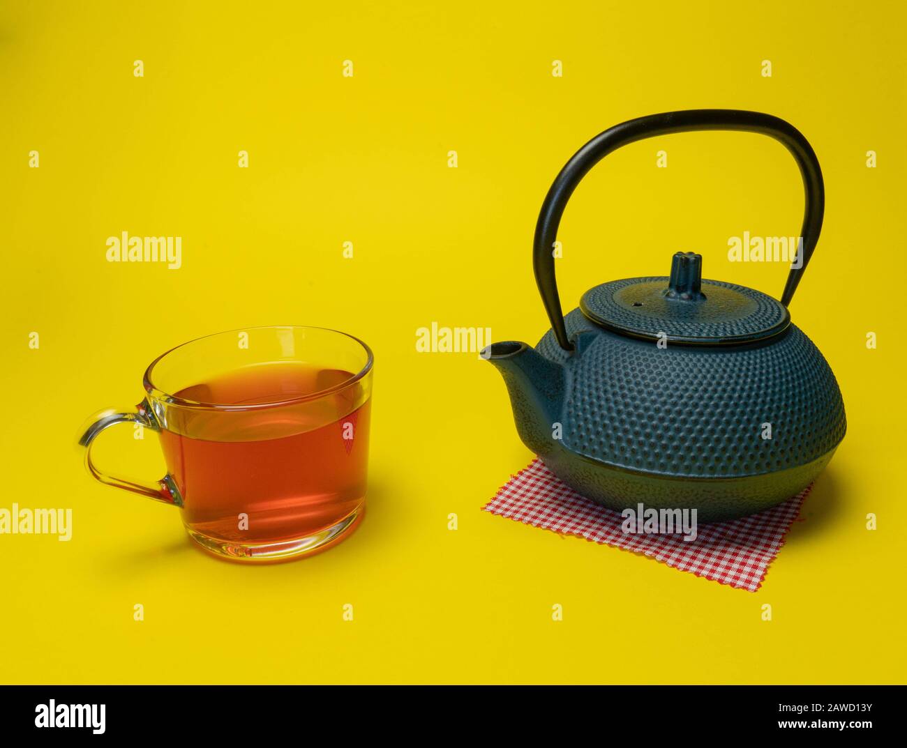 Préparation du thé, cérémonie du thé, tasse de thé rouge fraîchement préparé, lumière douce, fond jaune Banque D'Images