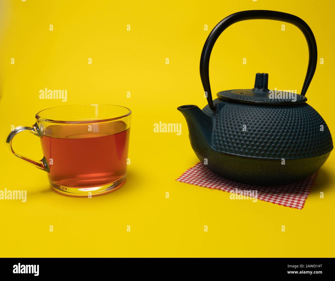 Préparation du thé, cérémonie du thé, tasse de thé rouge fraîchement préparé, lumière douce chaude, fond jaune Banque D'Images
