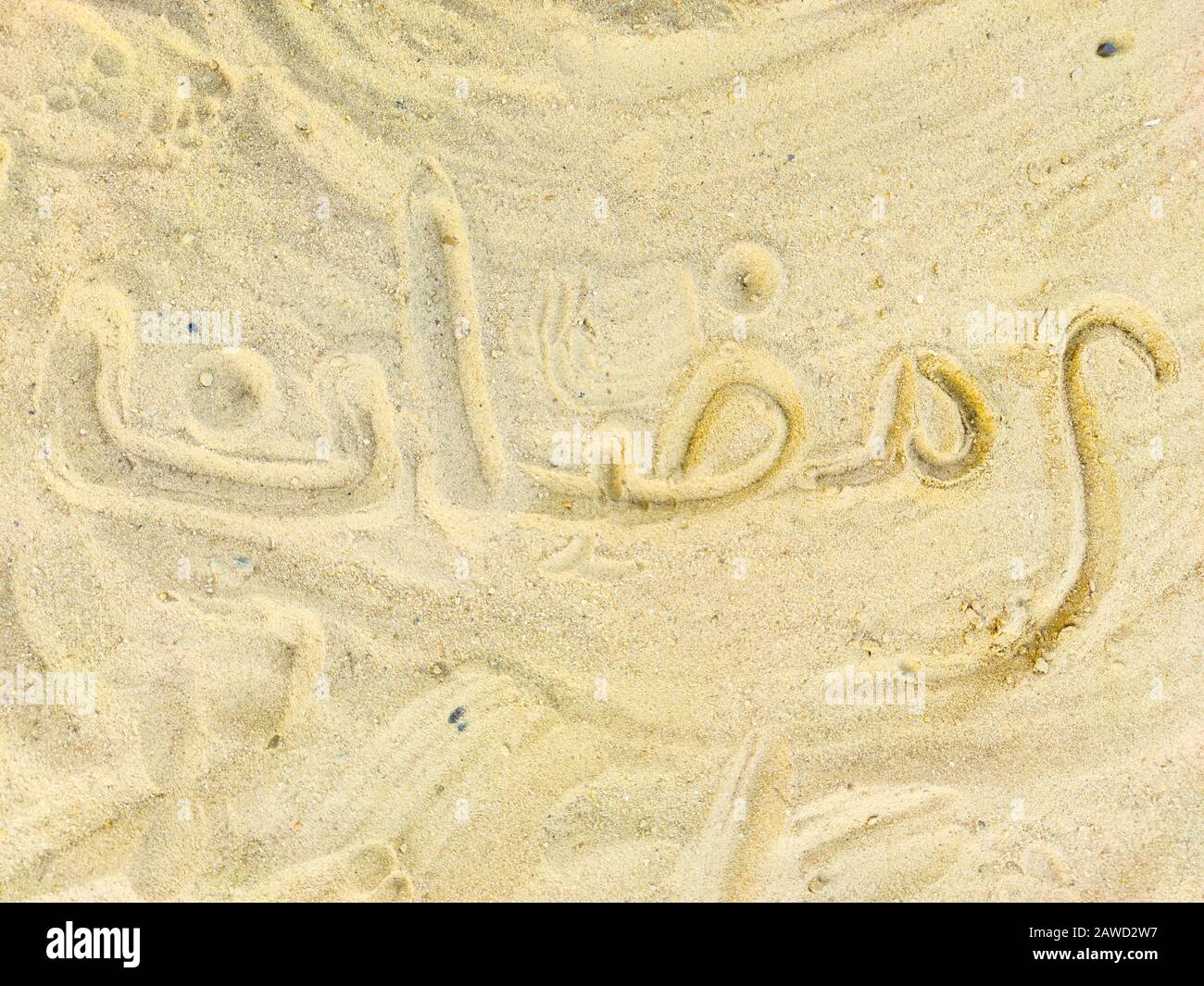 Mot Ramadan en arabe, écriture sur le sable doré chaud, lettrage. Arrière-plan de la carte de vœux Banque D'Images