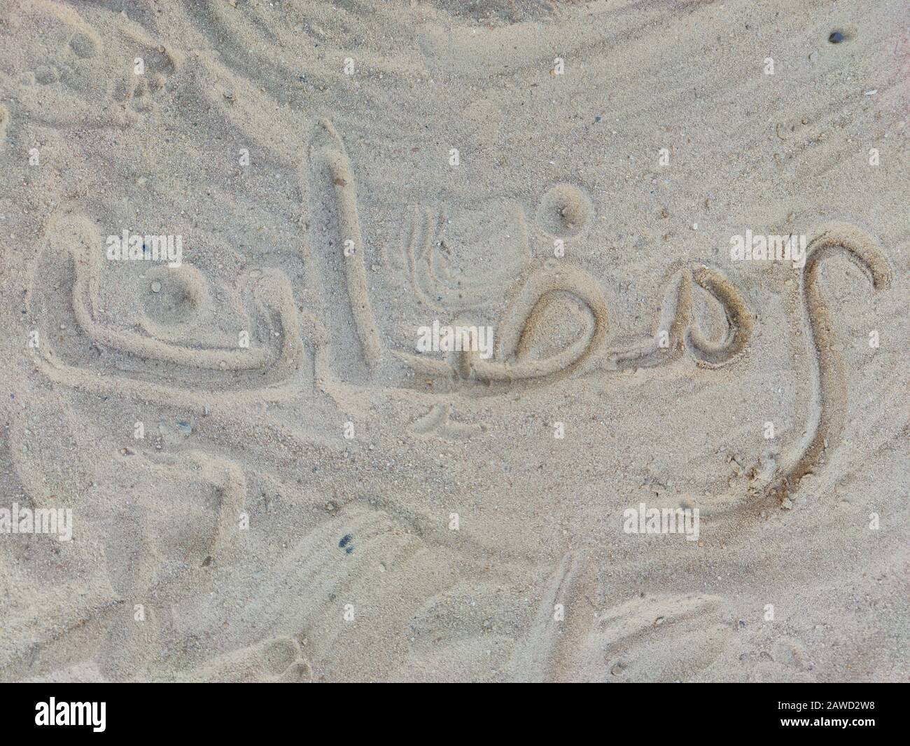 Mot Ramadan en arabe, écriture sur le sable doré chaud, lettrage. Arrière-plan de la carte de vœux Banque D'Images