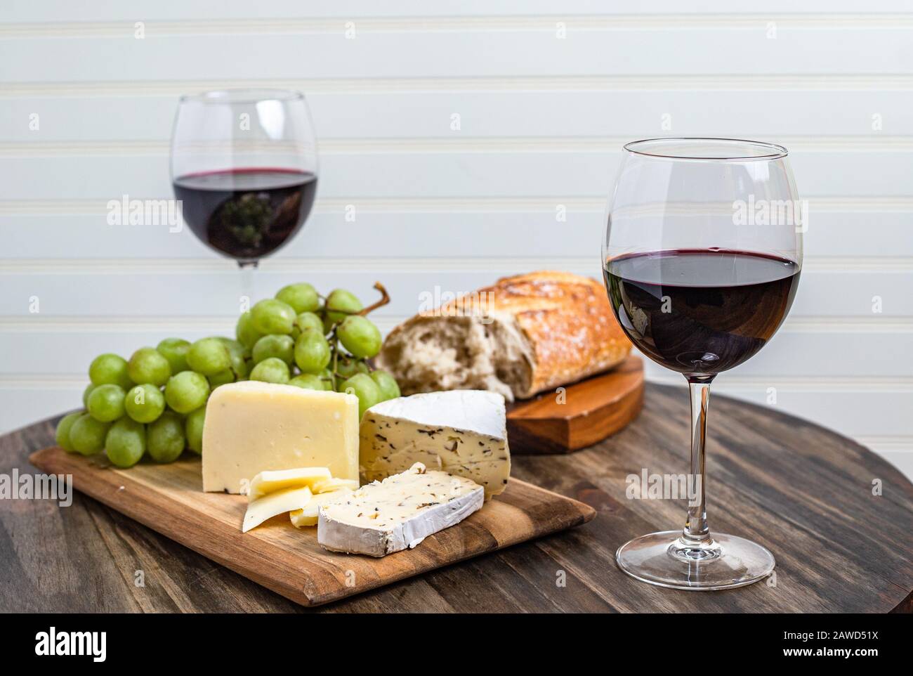 Plateau de vin et de fromage servi avec des raisins sur la surface du bois avec fond blanc Banque D'Images