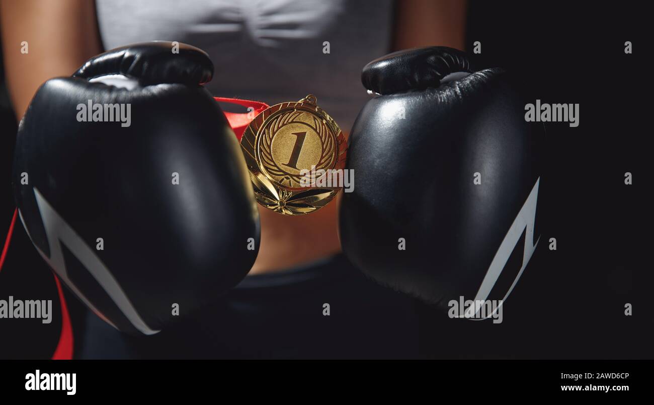 Les gants de boxe occupent la première place de la médaille d'or dans les mains de la femelle gagnante combattant. Banque D'Images