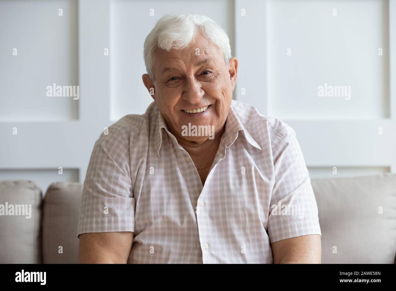 Portrait en tête de l'homme souriant et mûr se reposant sur un canapé Banque D'Images