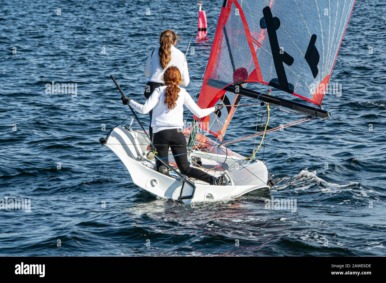 Deux filles voile petit voilier avec de longs cheveux rouges vue rapprochée de derrière. Travail d'équipe par des marins juniors en course sur le lac d'eau salée Macquarie. Banque D'Images