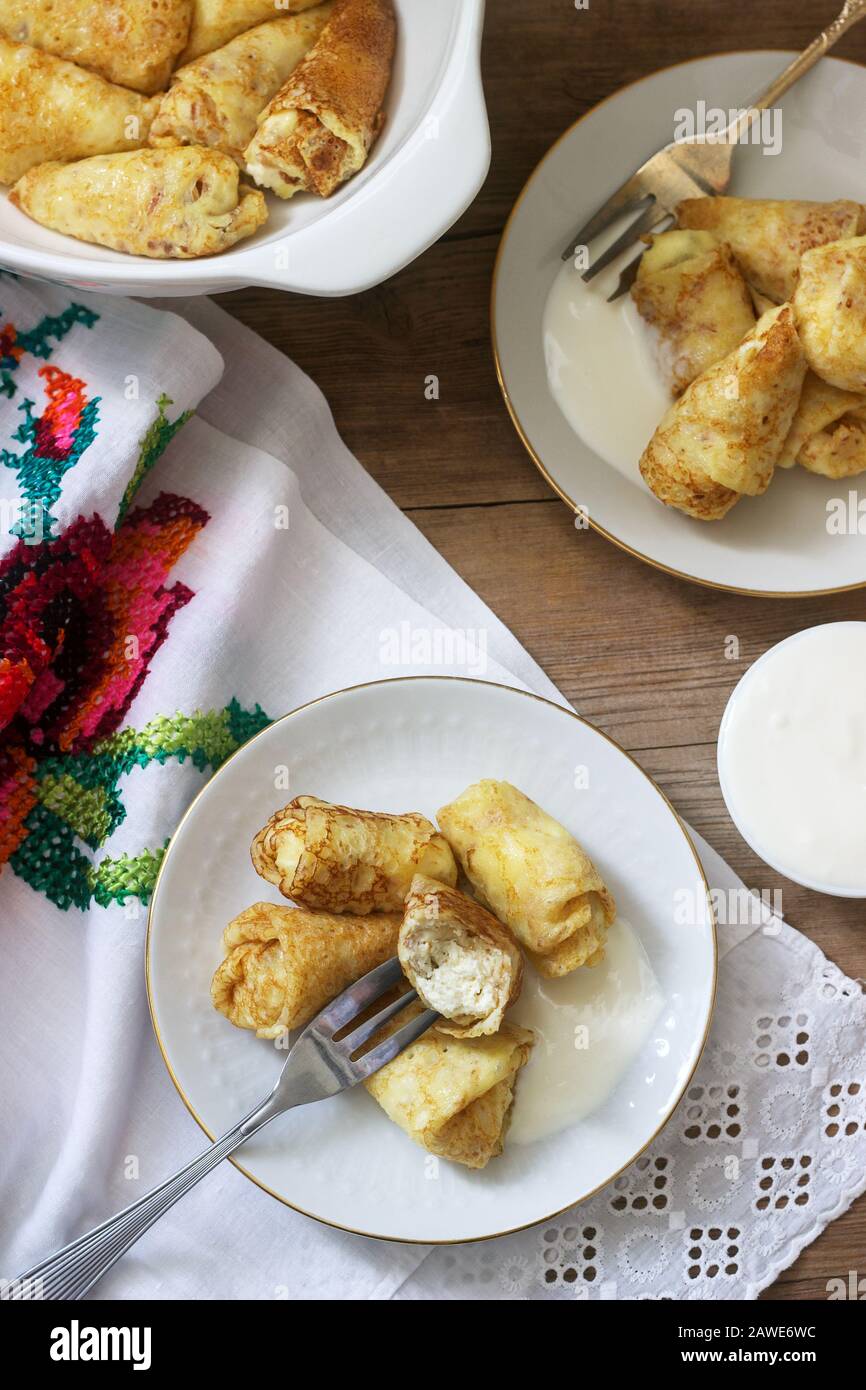 Crêpes maison farcies au fromage cottage avec des raisins secs, servies avec de la crème aigre et de la cerise. Banque D'Images