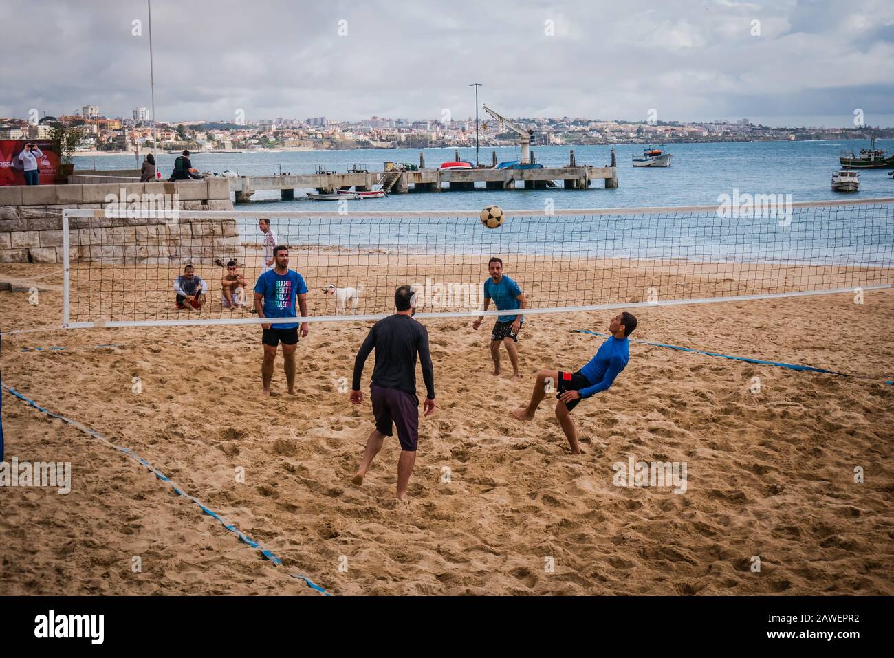 Les hommes jouant à la marche de la plage Praia da Ribeira, la plage principale de Cascais, qui fait face à la place centrale des villes et surplombe le port de pêche Banque D'Images
