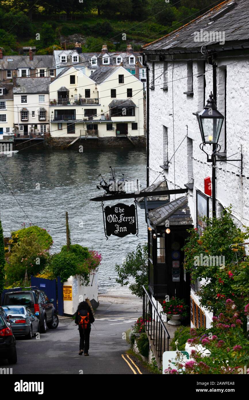 Femme transportant un sac à dos en descendant Hall Terrace, après l'Old Ferry Inn, River Fowey en arrière-plan, Bodinnick, près de Fowey, Cornwall, Angleterre Banque D'Images