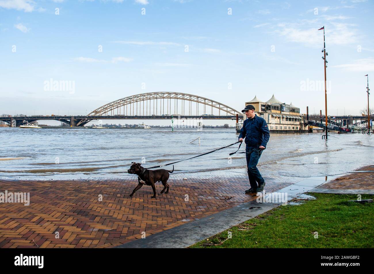 Un homme marchant avec son chien plus près de la zone d'inondation.les plaines d'inondation le long des rives du Rhin et d'autres grandes rivières devraient être sous l'eau dans des endroits plus tard ce week-end. Nijmegen est l'une des villes néerlandaises qui est maintenant affectée par ce haut niveau d'eau. La Waalkade, la zone plus proche de la rivière a été fermée à la circulation et on s'attend à ce que l'eau atteigne une hauteur de plus de 11 mètres au-dessus du niveau de la mer. L'eau du Rhin à Lobith, où le fleuve traverse les Pays-Bas, devrait atteindre environ 14 mètres au-dessus du PAN dans les jours à venir. NAP est la base utilisée t Banque D'Images