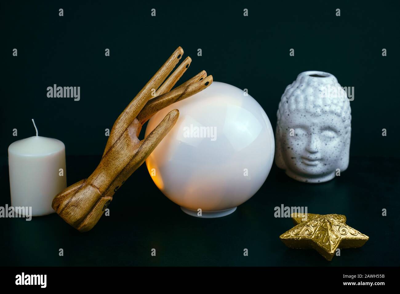 Ésotériques encore la vie avec une boule de cristal et main de bois, la tête de Bouddha en céramique statuette et bougie blanche sur un fond noir Banque D'Images