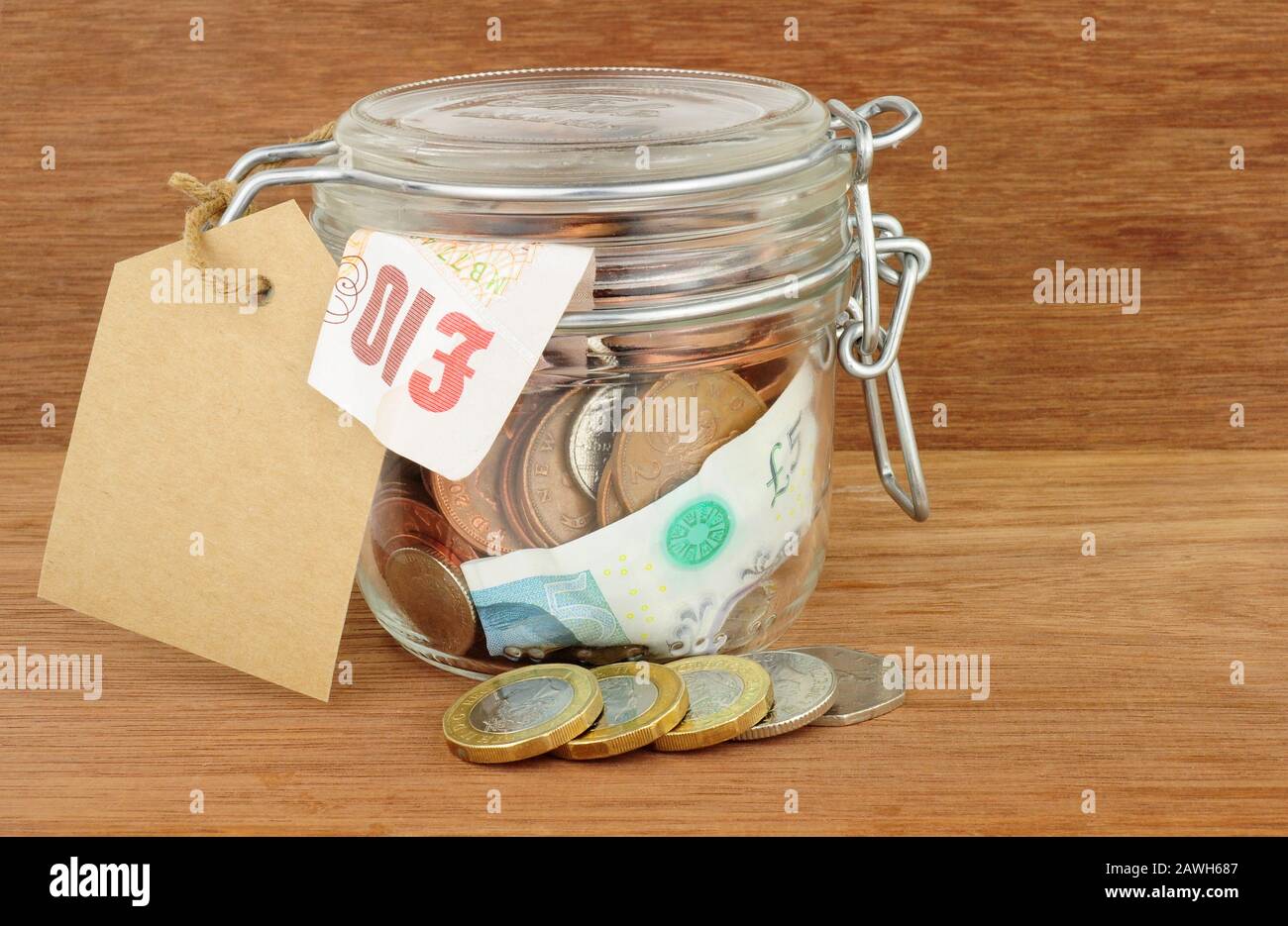 Bocal en verre rempli d'économies sur un fond de bois Banque D'Images