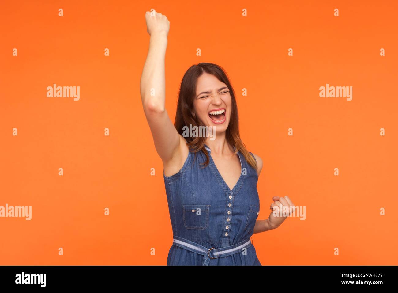Hooray, victoire! Joyeuse femme brunette enthousiaste en denim dansant en hurlant de l'excitation, admirant le succès, se sentant champion Banque D'Images