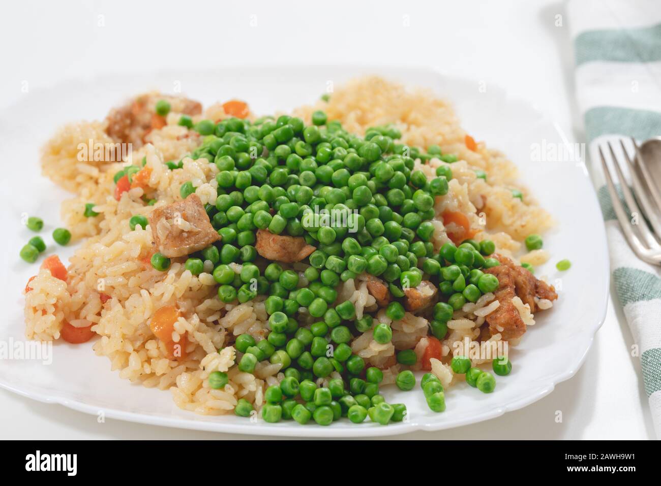 Riz avec viande et légumes gros plan sur une plaque sur fond blanc Banque D'Images