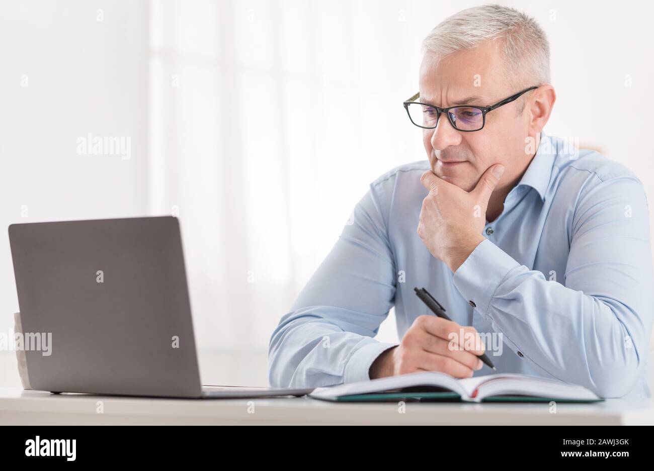 Homme senior utilisant un ordinateur portable à la maison, éducation en ligne Banque D'Images