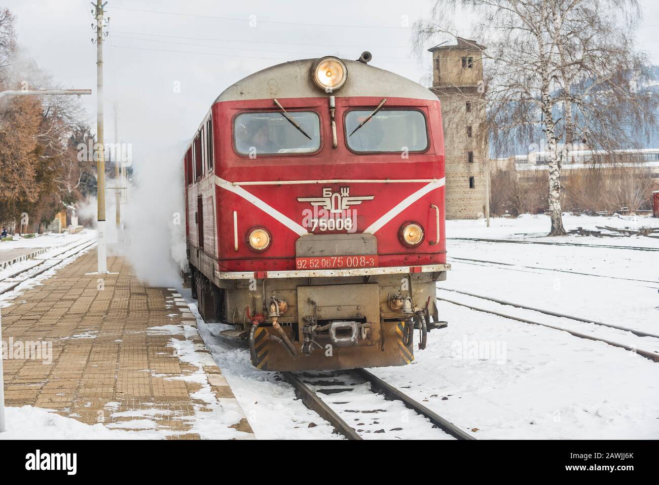 Gare de Velingrad, Bulgarie - 8 février 2020: Train avec locomotive rouge et wagons verts arrive à la gare. Banque D'Images