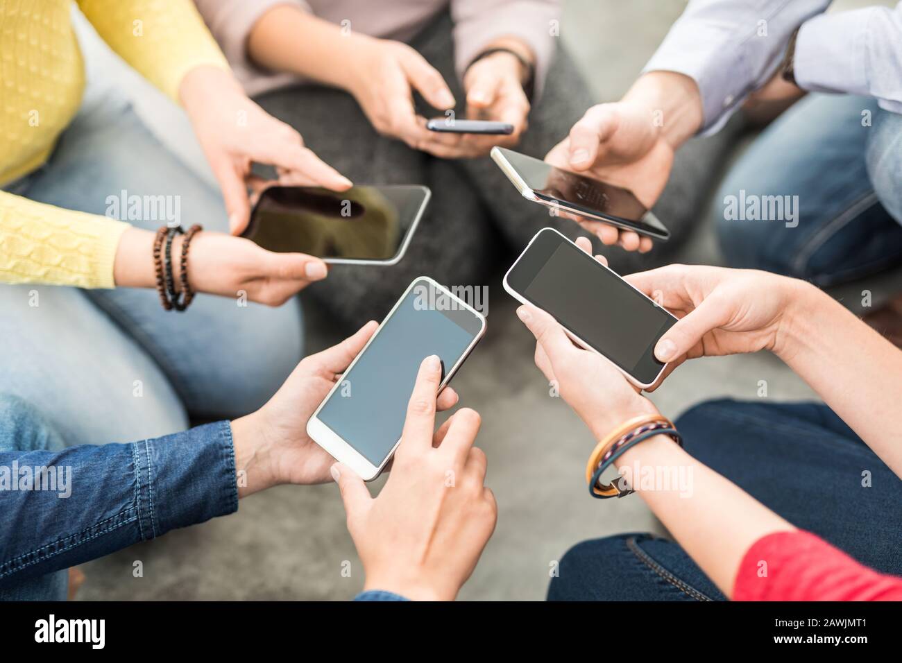 Groupe de jeunes vêtements taille basse tenant le téléphone entre les mains. Des amis qui s'amusent avec des smartphones. Banque D'Images