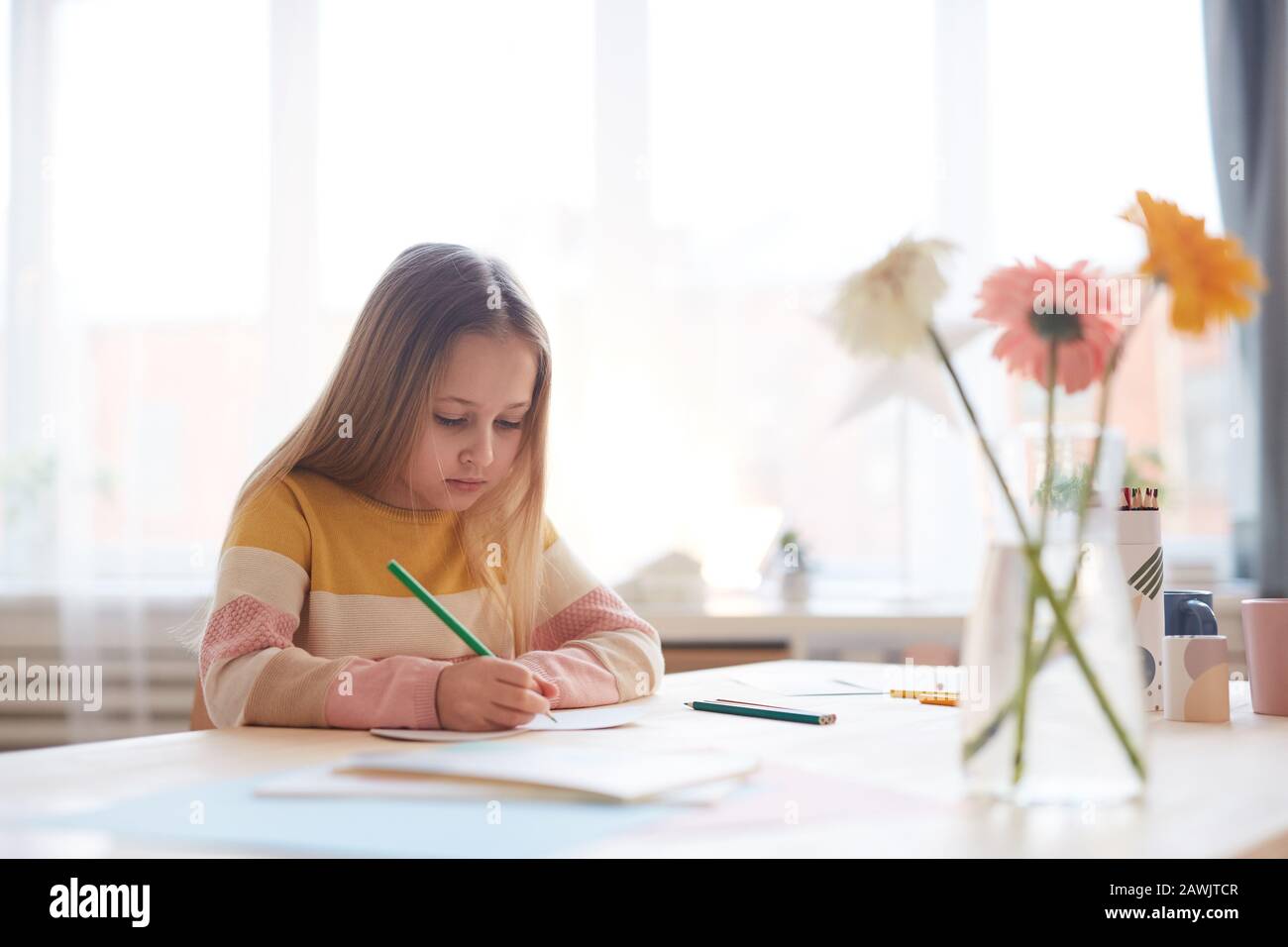 Portrait de la petite fille mignonne dessin des images ou faire des devoirs tout en étant assis à la table dans l'intérieur de la maison, espace de copie Banque D'Images