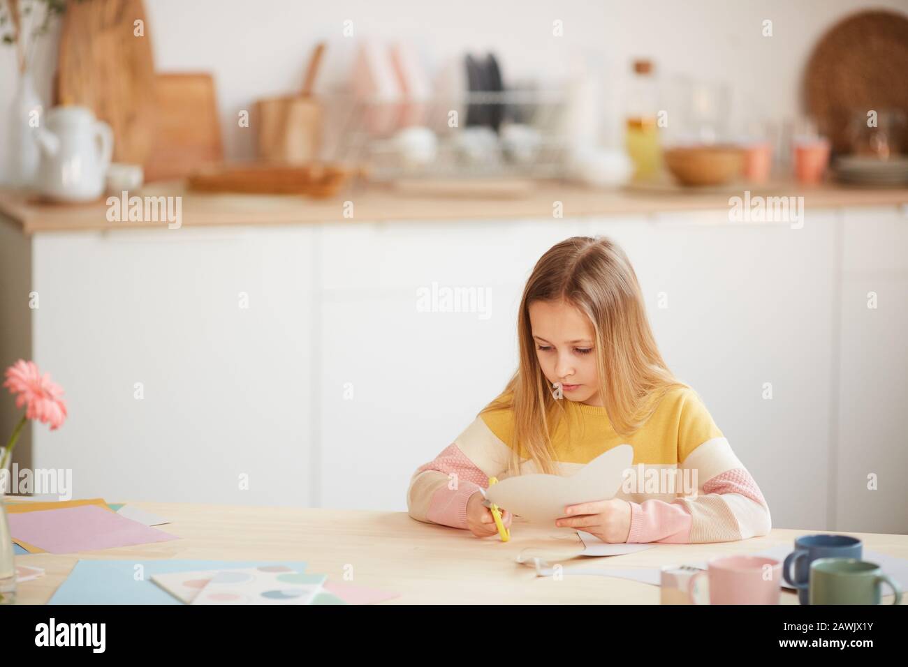 Portrait grand angle de jolie fille faisant carte de vacances pour la fête Des Mères ou Saint Valentin en étant assis à la table dans un intérieur confortable maison, espace de copie Banque D'Images