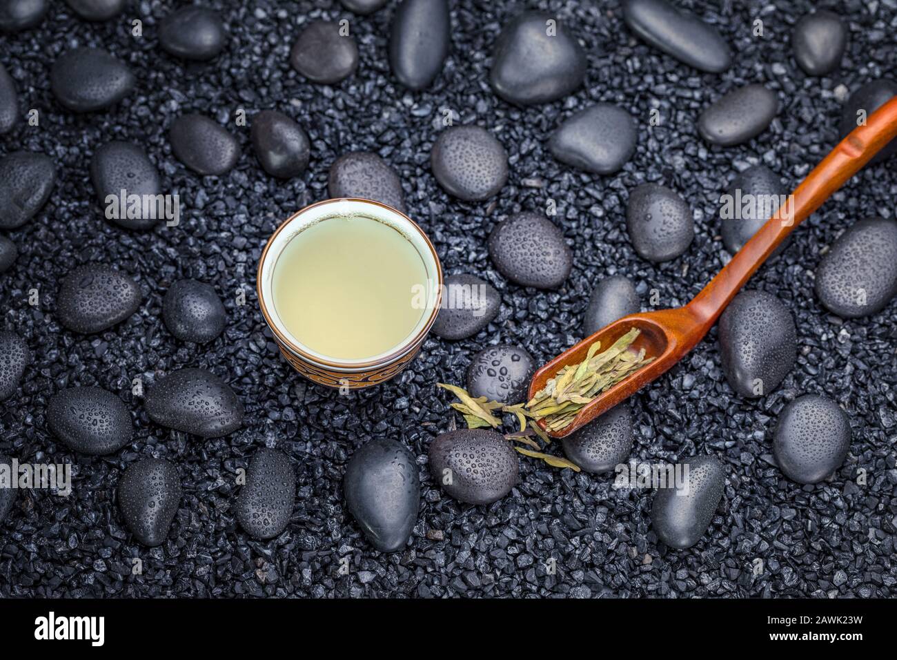 Tasse de thé vert, thé Longjing de Hangzhou, Zhejiang, et feuilles de thé vert sur galet en pierre noire. Banque D'Images