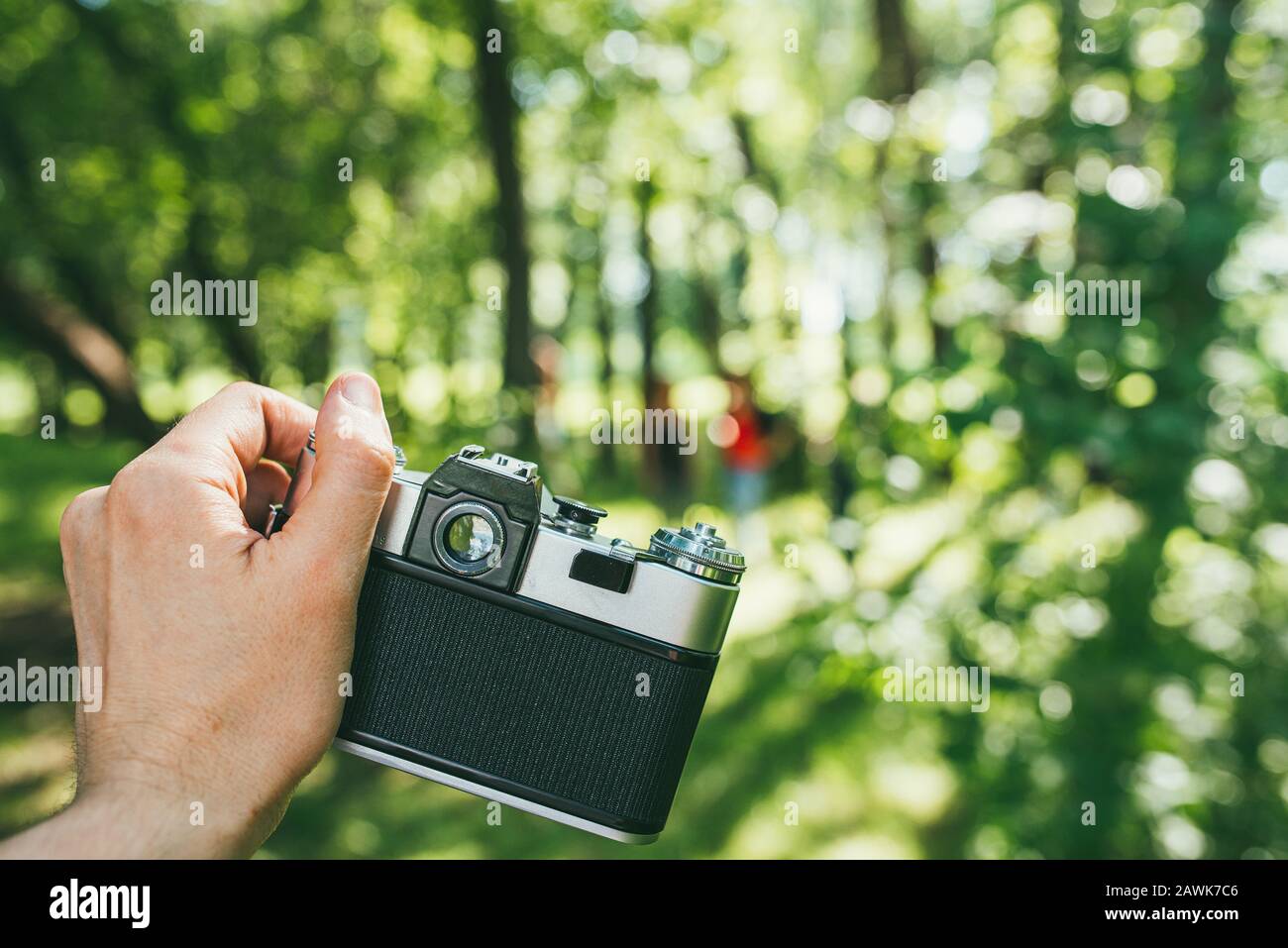 La main d'un homme tient un vieux film de caméra et photographie un paysage vert. Première personne de la vue POV Banque D'Images