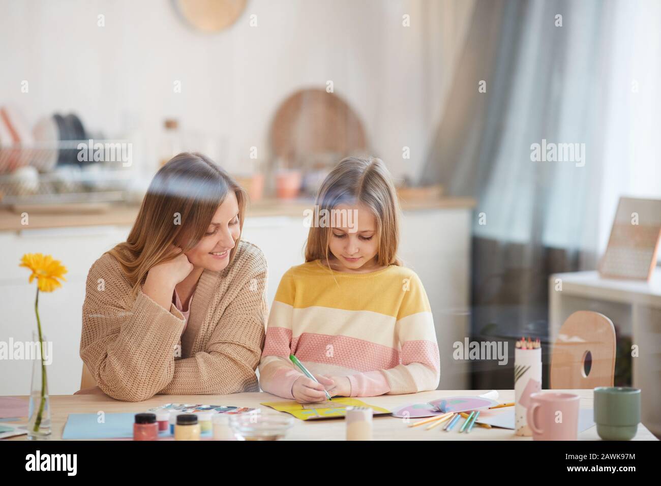 Portrait de mère mûre dans des tons chauds aidant une fille mignonne avec projet d'art et d'artisanat dans l'intérieur de la maison, espace de copie Banque D'Images