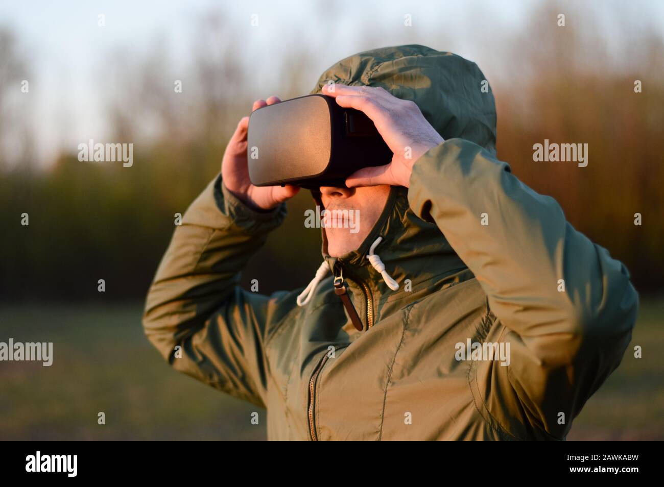 Jeune soldat tenant les mains sur des lunettes de réalité virtuelle, regardant la distance pendant une simulation d'une situation de combat Banque D'Images