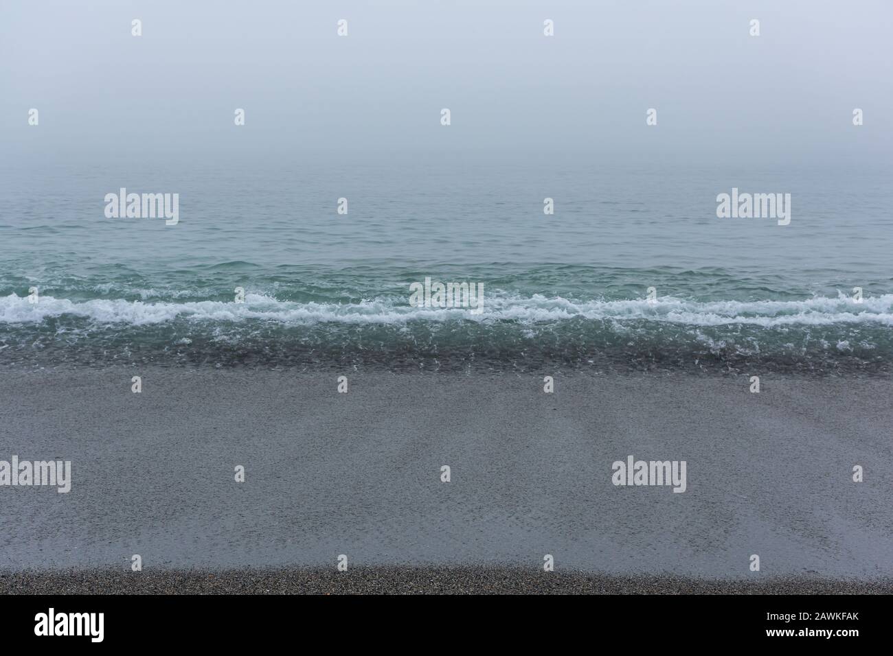 Plage de sable avec la mer calme une journée de brume Banque D'Images