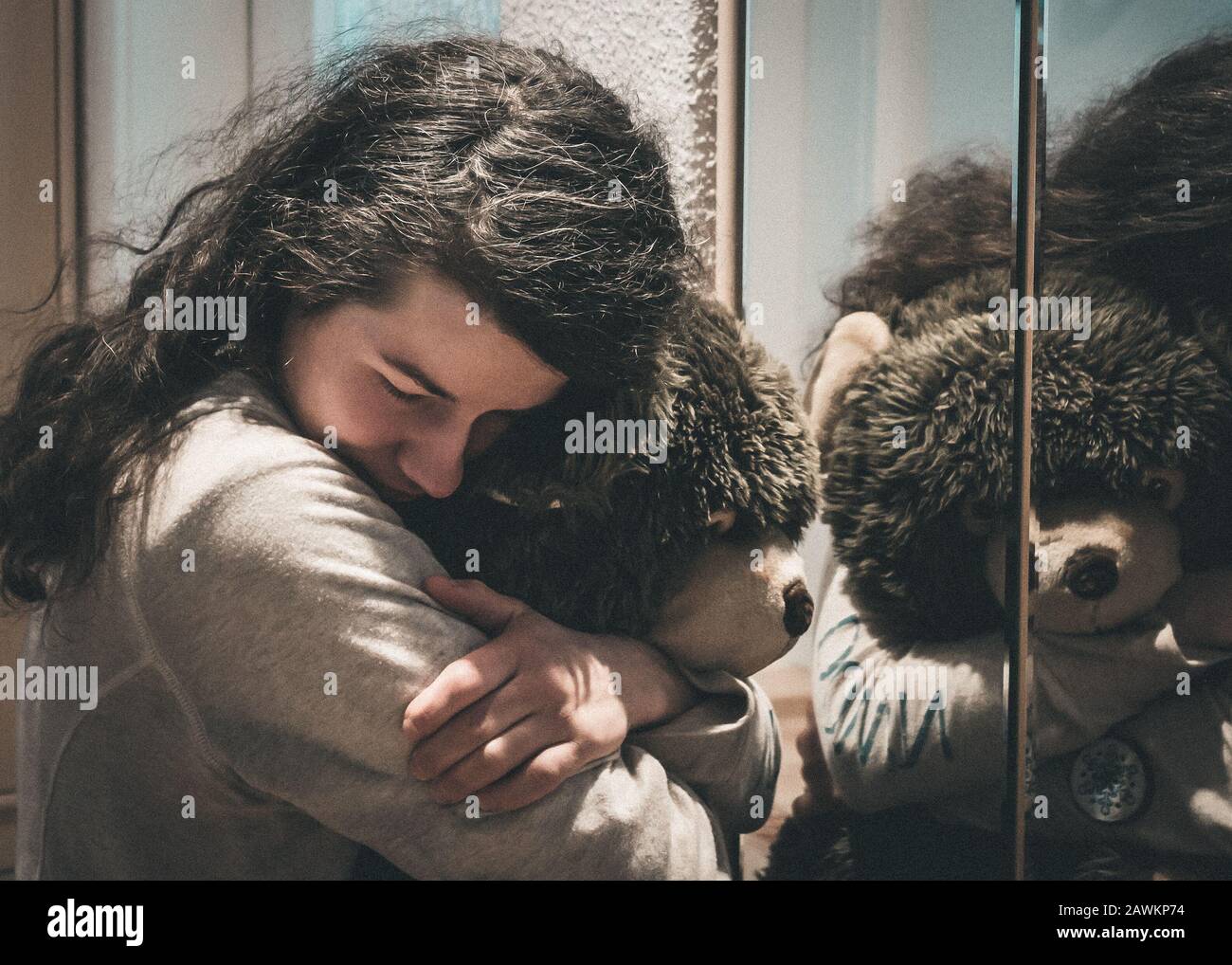 Emotions Profondes Une Femme Perdue Dans Le Chagrin Et La Tristesse Embrassant Un Ours En Peluche Devant Un Miroir Photo Stock Alamy