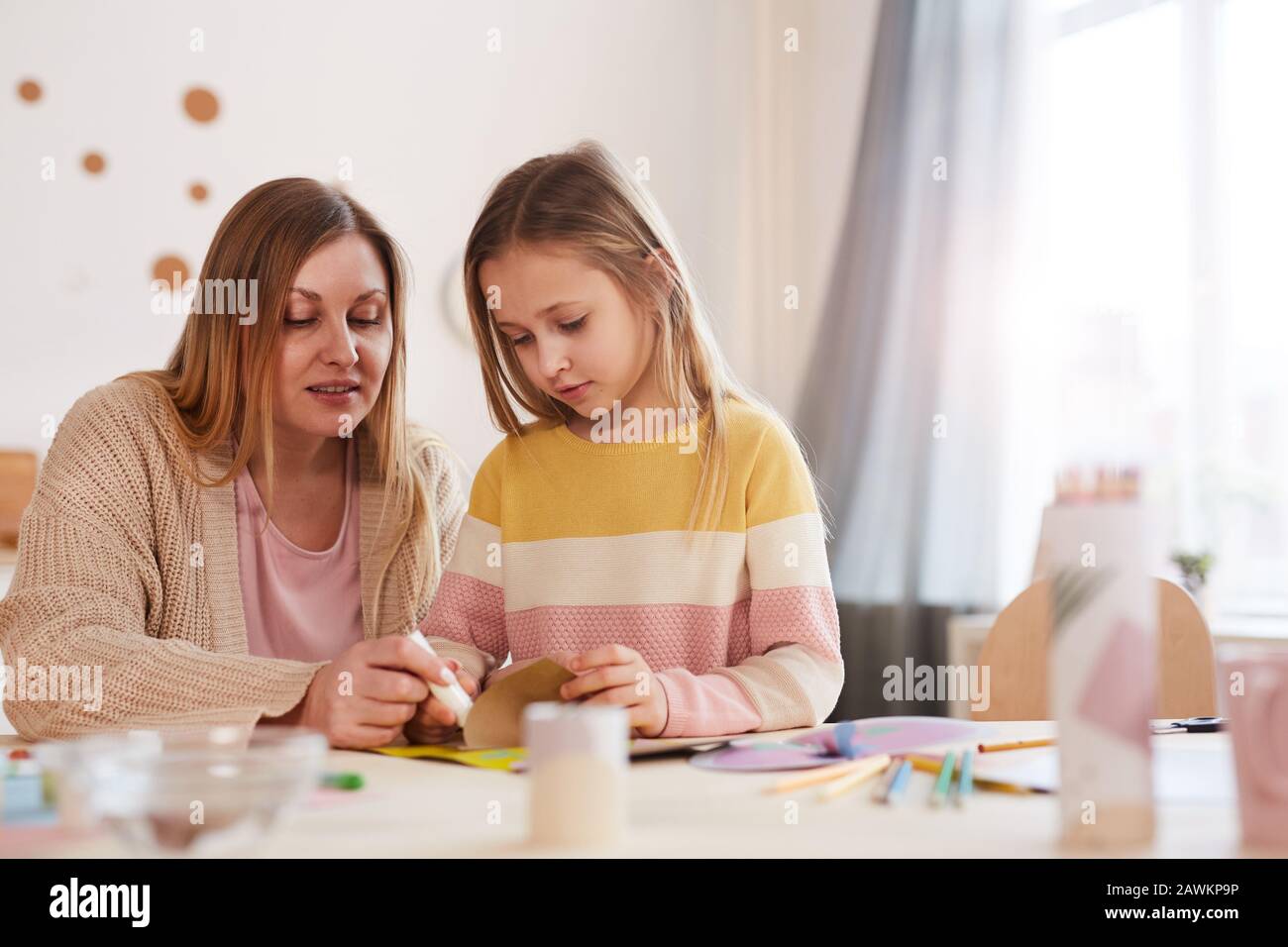 Portrait de mère mûre aux tons chauds, avec art et artisanat, fille mignonne à l'intérieur de la maison, espace de copie Banque D'Images