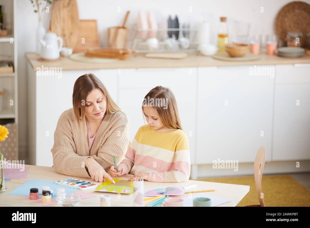 Portrait à grand angle de la mère mûre aidant la fille mignonne avec des projets d'art et d'artisanat dans l'intérieur de la maison, espace de copie Banque D'Images