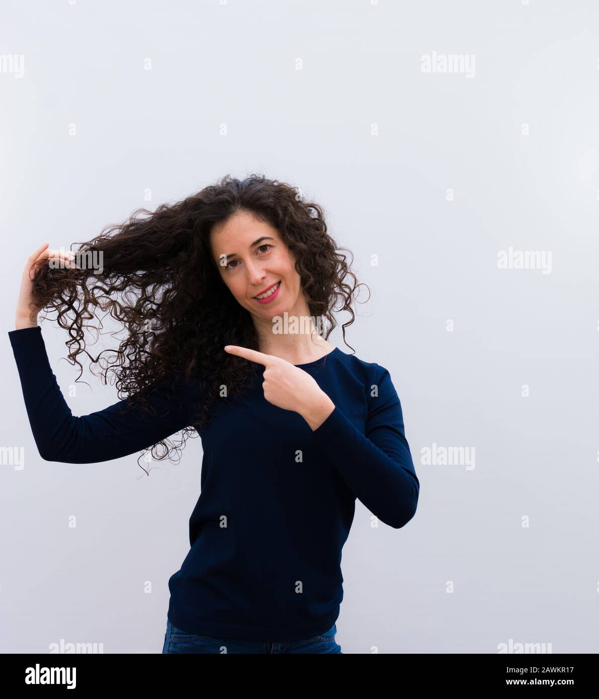 Jeune jolie femme avec des cheveux noirs et frisés montrant ses cheveux frisés Banque D'Images