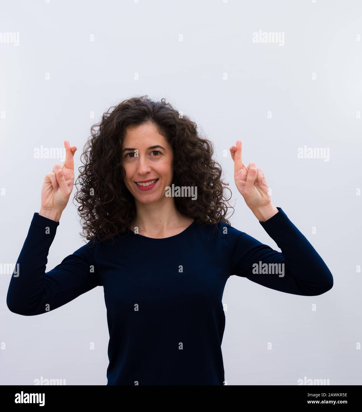 jeune jolie femme sentant nerveux et pleine d'espoir, croisant les doigts, priant et espérant avoir bonne chance contre Banque D'Images