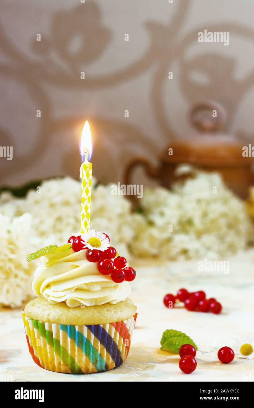 Doux cupcake festif avec crème et baies et une bougie un fond clair Banque D'Images