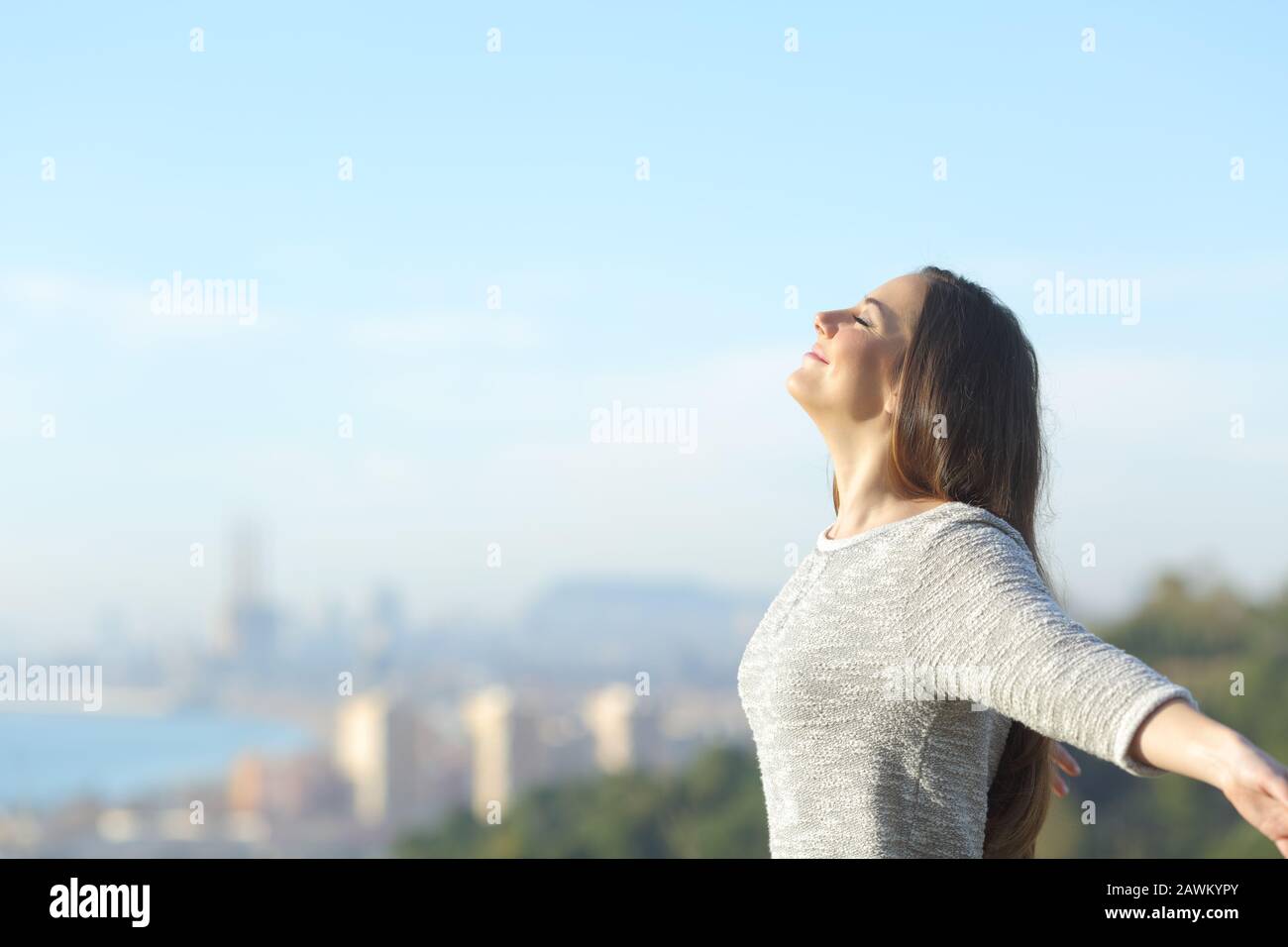 Profil d'une femme qui respire de l'air profondément frais avec une ville en arrière-plan Banque D'Images