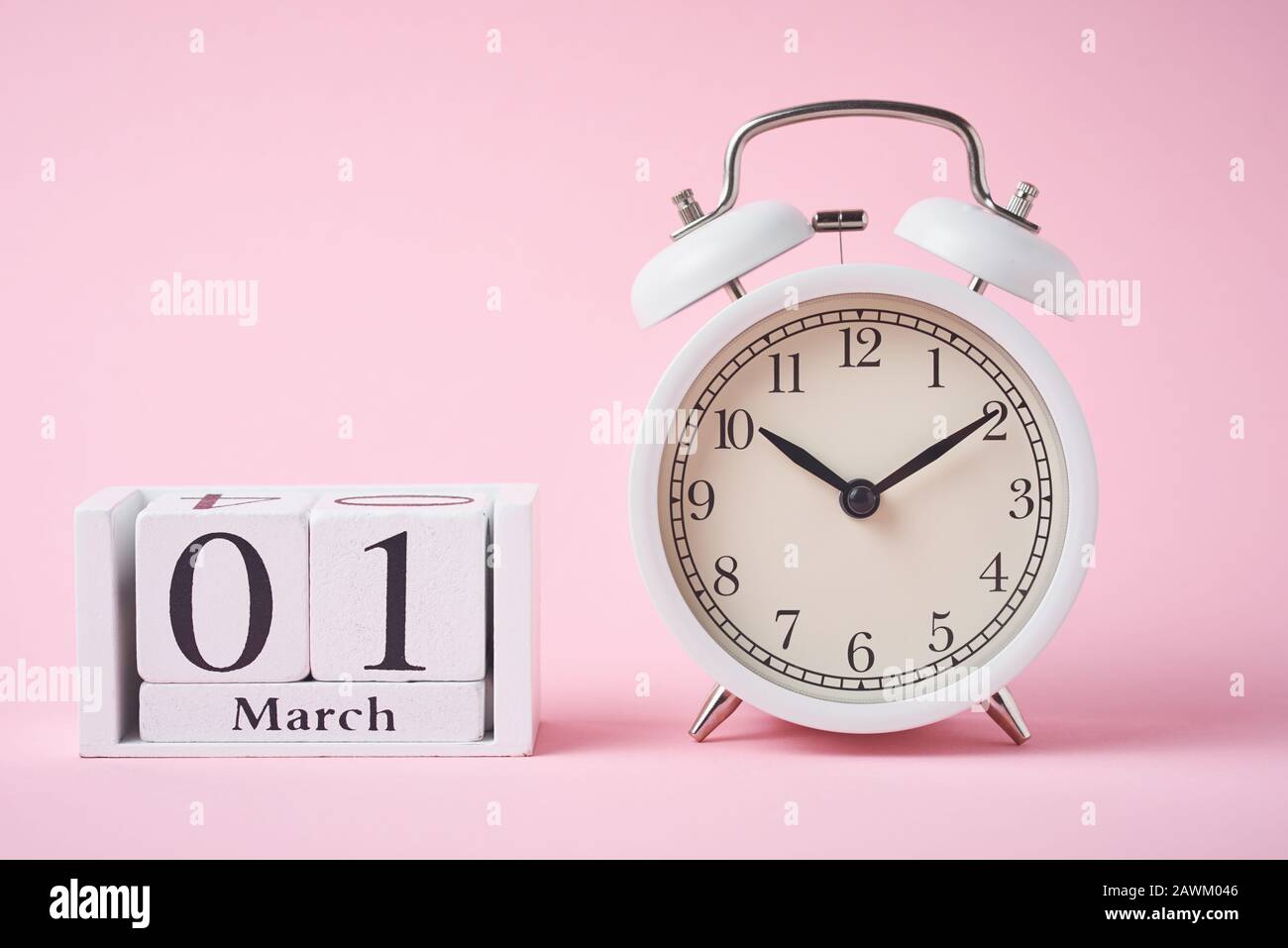 Réveil rétro blanc avec cloches et blocs calendrier en bois avec date du 1er mars sur fond rose Banque D'Images