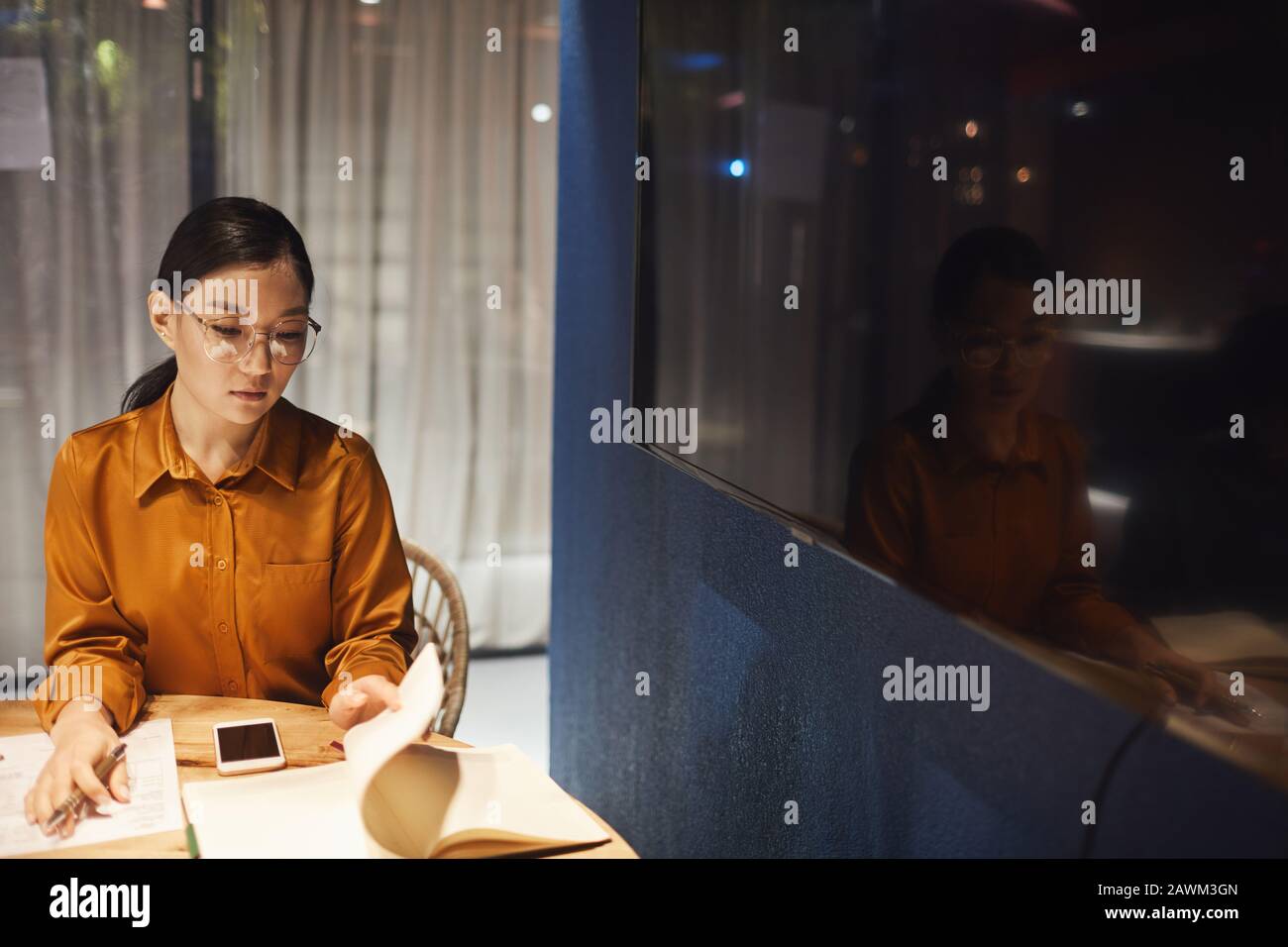 Portrait à grand angle de la femme d'affaires asiatique contemporaine travaillant au bureau dans l'intérieur sombre du bureau, espace de copie Banque D'Images