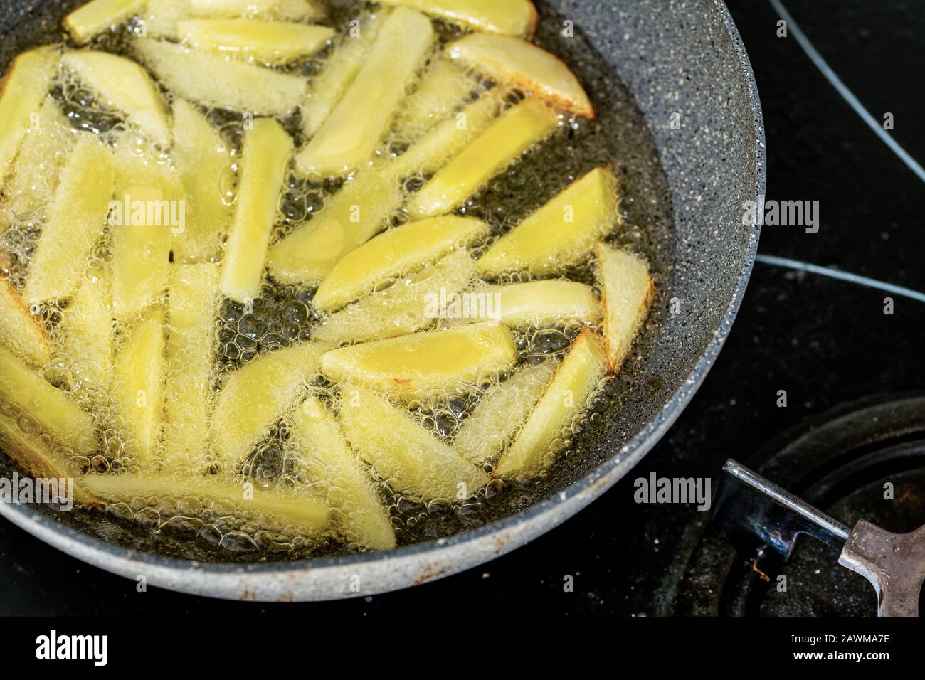 Les frites frire dans de l'huile végétale dans la poêle de la cuisinière Banque D'Images