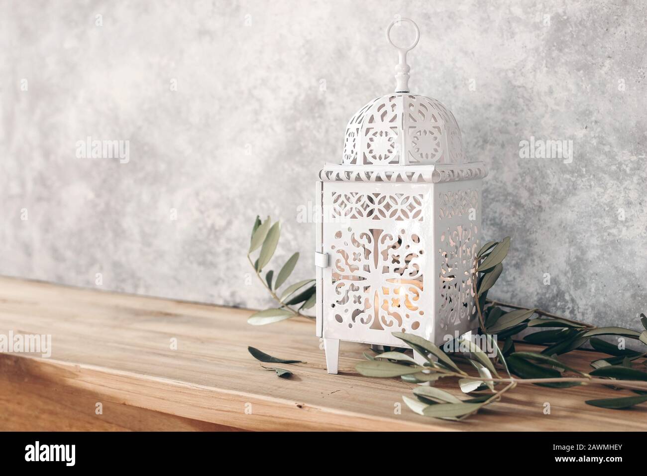 Blanc décoratif marocain, lanterne arabe. Feuilles d'olive vertes, branches sur une vieille table en bois, fond flou de mur de grunge,. Carte de vœux pour musulman Banque D'Images