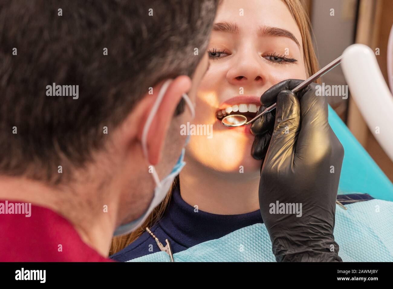 le dentiste examine les dents d'une fille patient avec un miroir Banque D'Images