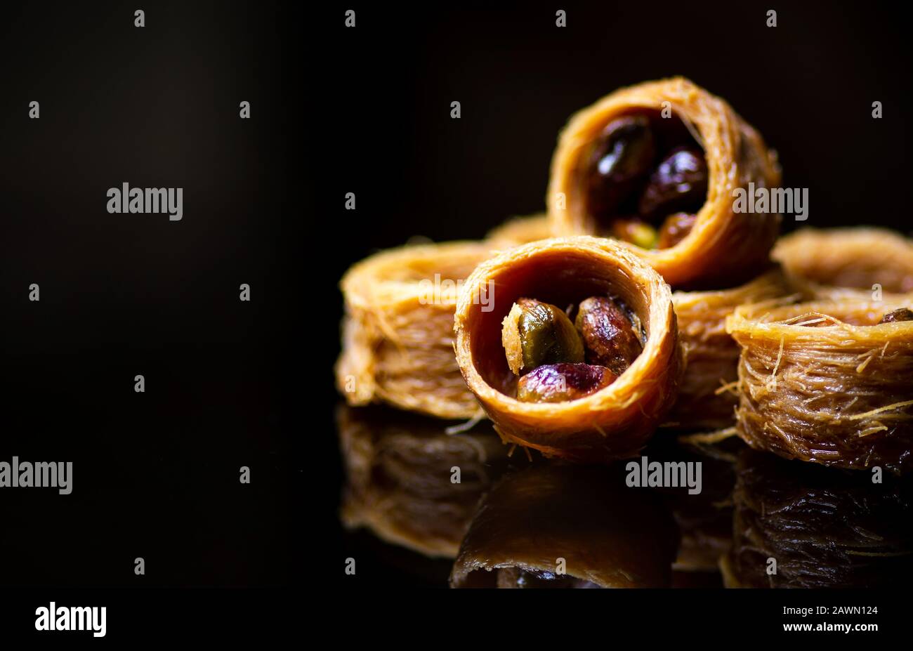 Dessert arabe avec pistache réfléchie sur fond sombre Banque D'Images