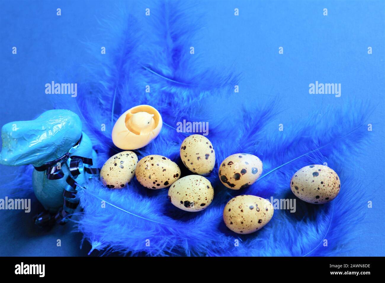Concept de Pâques. Œufs de caille et lapin bleu sur plumes d'oiseaux bleus dans une couleur tendance sur un fond bleu. Couleur tendance 2020. Vue de dessus. Espace de copie Banque D'Images