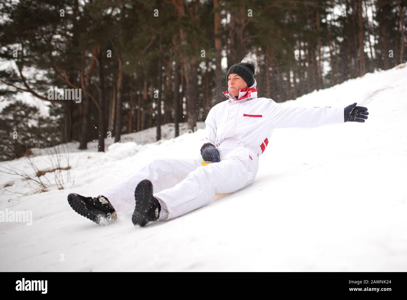 Une femme adulte se déplace sur la glace de traîneau à partir d'une montagne escarpée. Plaisir en hiver. Banque D'Images