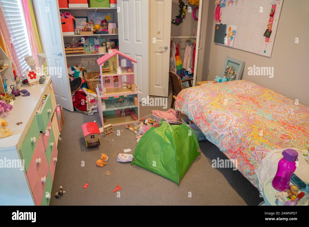 À l'intérieur d'une chambre de petite fille désordonnée mais bien utilisée avec des jouets et des choses éparpillées et des portes de placard ouvertes. Banque D'Images