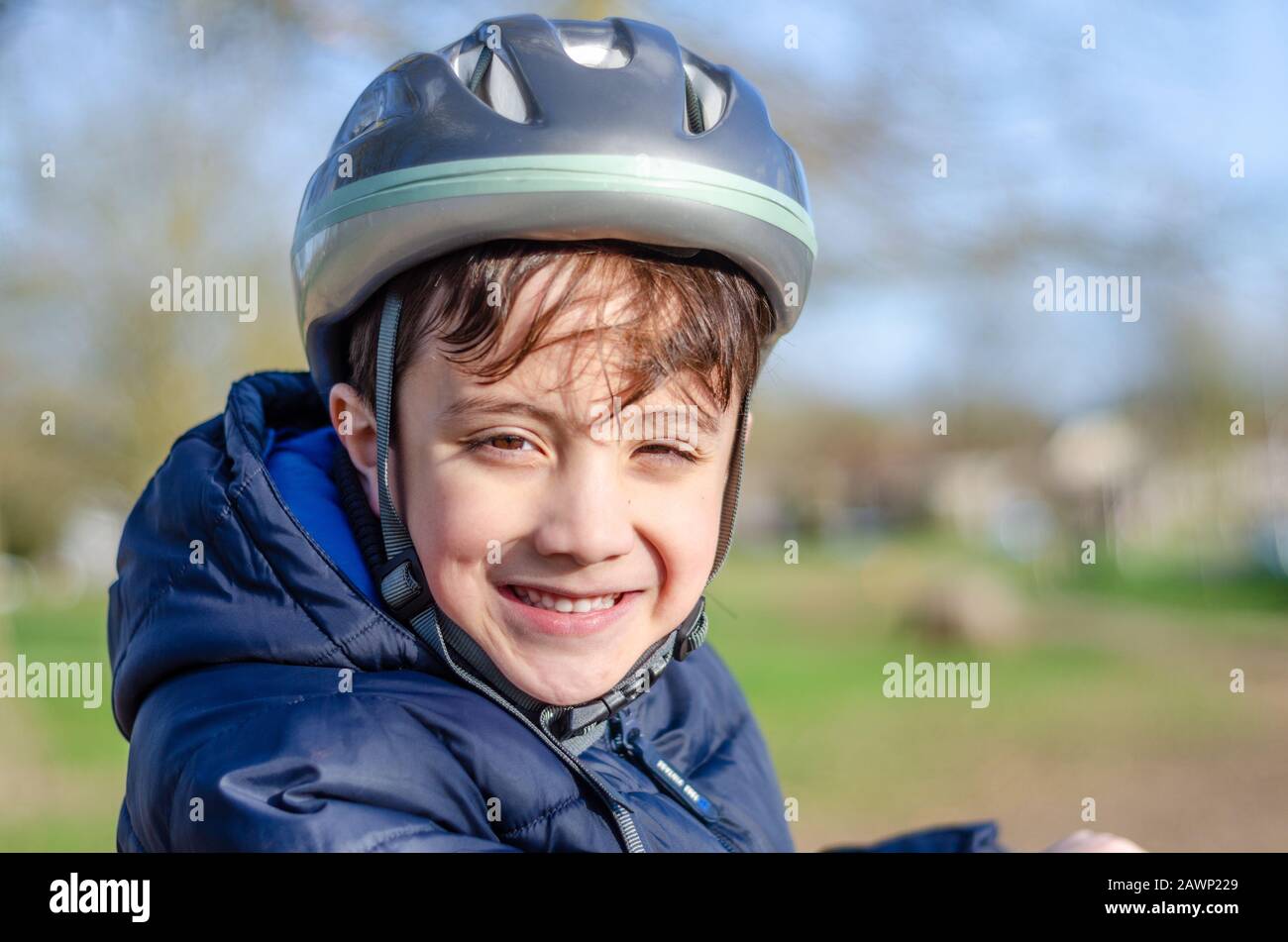 Portrait d'un jeune garçon à l'extérieur portant un casque de vélo et souriant. Banque D'Images