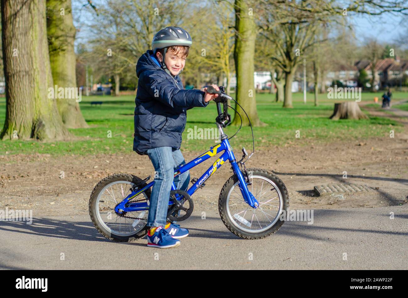 Portrait d'un jeune garçon heureux avec sa moto, portant un casque de vélo dans le parc. Banque D'Images